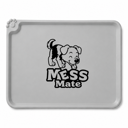 A gray rectangular pet training mat with rounded corners, featuring a black cartoon puppy graphic and the words 'MESS Mate' printed in the center. A small paw print detail is visible on the top-left edge.