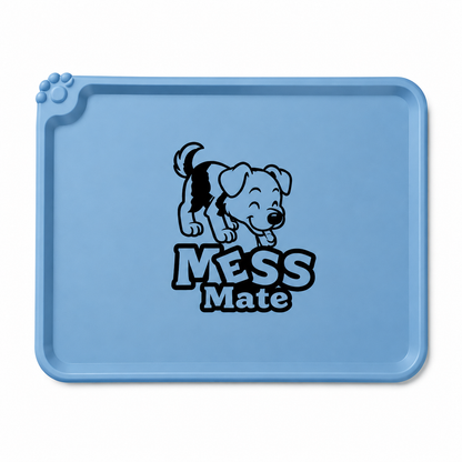 A light blue rectangular pet training mat with rounded corners, featuring a black cartoon puppy graphic and the words 'MESS Mate' printed in the center. The mat has a raised paw print detail on the top-left corner and is shown against a plain white background.